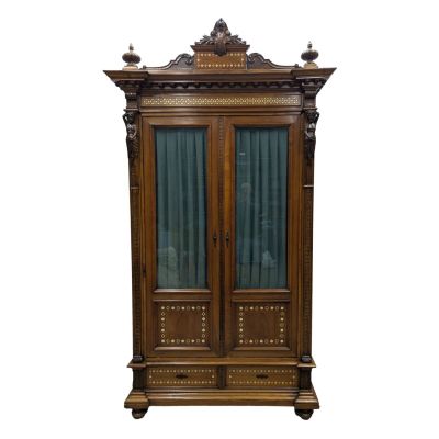 une armoire ancienne en bois, dotée de portes vitrées et de sculptures ouvragées