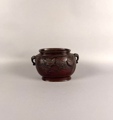 un petit vase marron muni de deux anses, posé sur un fond blanc