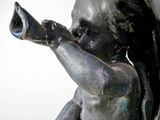 a statue of a baby holding a bottle in its hand