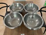 four stainless steel bowls sitting on top of a wooden table