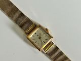an image of a gold wrist watch with a white face