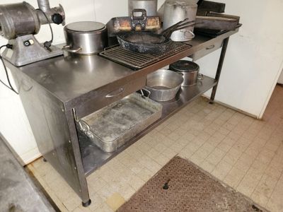 une table en métal sur laquelle sont posés des casseroles et des poêles