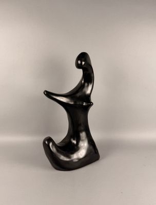une sculpture noire représentant une personne assise sur une chaise