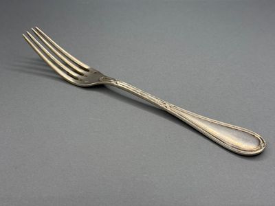 une fourchette plaquée argent posée sur une surface grise avec un fond noir