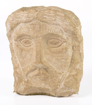 une tête d'homme sculptée dans la pierre, avec une croix sur le front