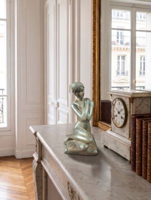 une statue représentant une femme assise sur une table en marbre
