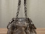 leather handbag on a wooden table with a curtain in the background