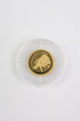une pièce d'or dans un étui en plastique transparent posé sur une surface blanche