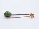 a close up of a pair of hair pins with a green bead