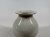 a gray vase with a brown rim sitting on a table