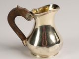 an old silver pitcher with a wooden handle on a white surface