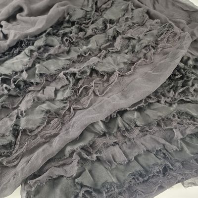 a close up of a gray scarf on a bed