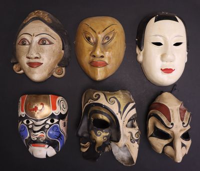 Plusieurs masques de différentes couleurs sont alignés sur une surface noire
