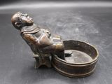 figurine en bronze représentant un homme assis sur un tabouret, tenant un bol d'eau