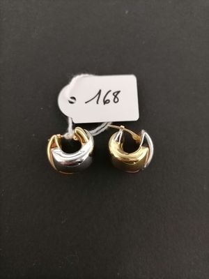 a pair of gold and silver earrings on a black surface