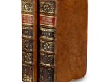 two old books sitting on top of each other on a white surface