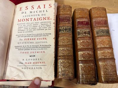 une personne tenant un livre devant une pile de livres