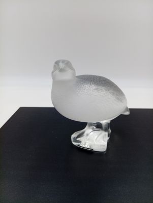 un oiseau en verre transparent posé sur une table noire