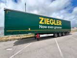 a green semi trailer parked in a parking lot
