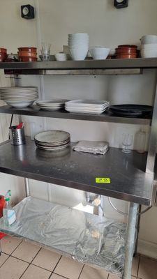 une étagère en métal sur laquelle sont posés des plats, dans une cuisine