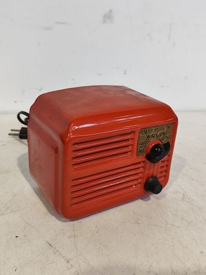 une vieille radio rouge posée sur une table blanche