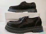 chaussures en cuir noir pour homme, avec semelles en caoutchouc noires, présentées dans une boîte blanche