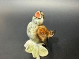 une figurine représentant un oiseau perché sur une feuille