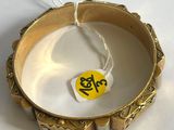 a gold bracelet with a tag on it on a white surface