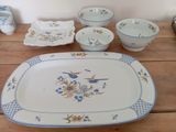 a table with a plate, bowl, cups, and a bowl on it