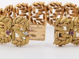 a close up of a gold bracelet with pink stones on it