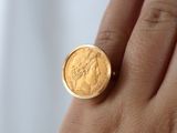 someone is holding a gold coin in their hand on a white background