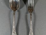 two silver spoons and a fork sitting on a table