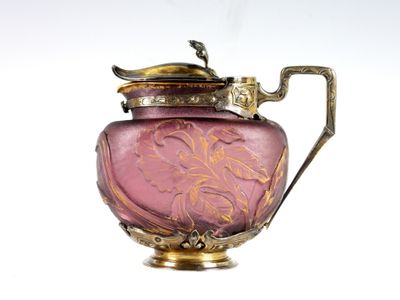 a pink glass vase with a gold handle on a white background