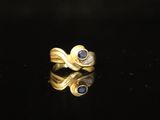 an image of a gold ring with blue sapphires on a black surface