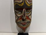 a close up of a mask on a stand on a white surface