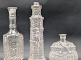three clear glass bottles sitting next to each other on a table