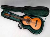 une guitare dans un étui, posée sur une surface blanche