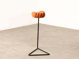 an orange chair sitting on top of a metal stand in a room