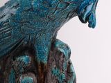 sculpture of a bird perched on a tree stump with a white background