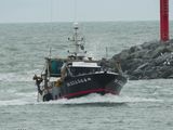 un bateau noir et rouge dans l'eau, près d'un phare