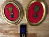 two framed medals and a cell phone on a wooden table