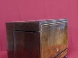 boîte en bois montée sur roulettes, posée sur une surface rouge, avec un fond rouge