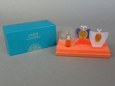 deux flacons de parfum posés sur un présentoir devant une boîte bleue
