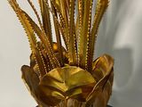 a gold vase with some plants in it on a black stand