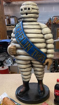 a statue of a man with a sash and a bottle of soda
