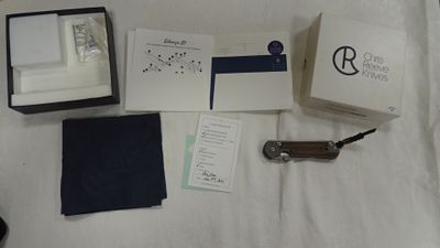 une boîte contenant une montre, un couteau de poche et d'autres objets, posée sur un lit