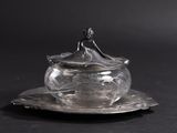 an antique silver plate with a lid and saucer on a black background