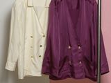 deux vestes suspendues à un porte-manteau devant un mur rose et blanc