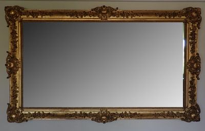 un miroir à cadre doré accroché au mur au-dessus d'un lavabo