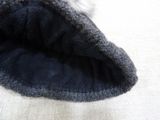 a black hat with a white pom pom on top of it